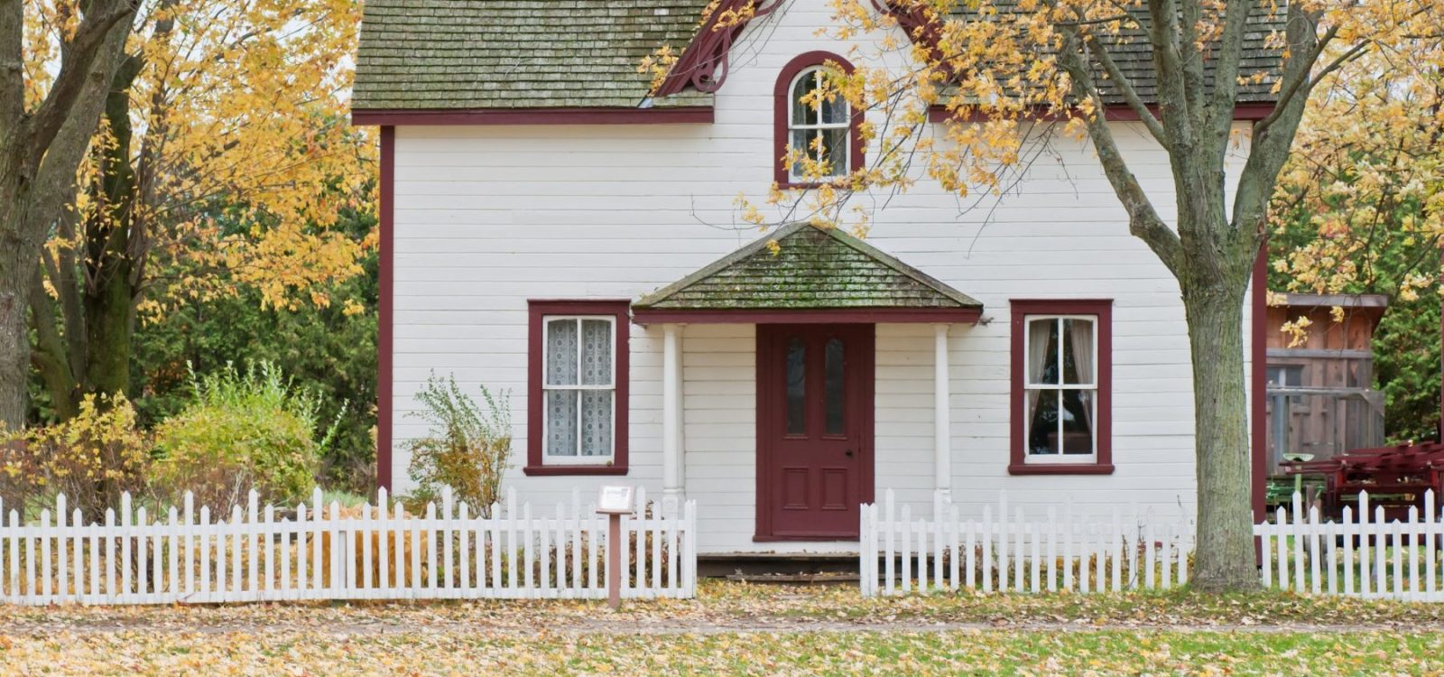 A home with a white fence and trees around it
