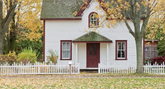 A home with a white fence and trees around it